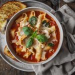 Delicious crock pot lasagna soup served with fresh basil and garlic bread on a rustic table